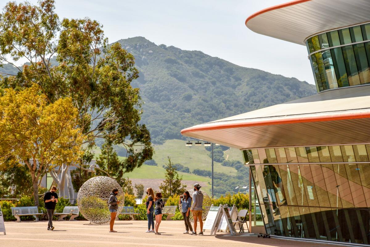 Students outside a university building with green hills in the background