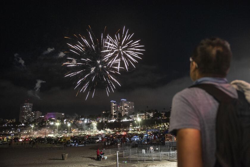 Crowds watch illegal fireworks fired from the parking lot of the Santa Monica Pier on July 4, 2021 in Santa Monica. ( Nick Agro / For The Times )
