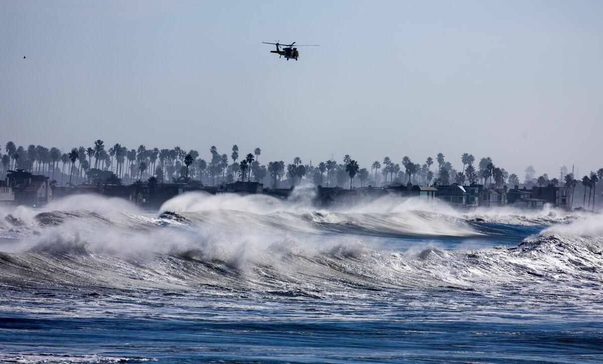A Ventura County fire helicopter patrols the coastline over heavy surf south of Ventura Pier on Thursday.