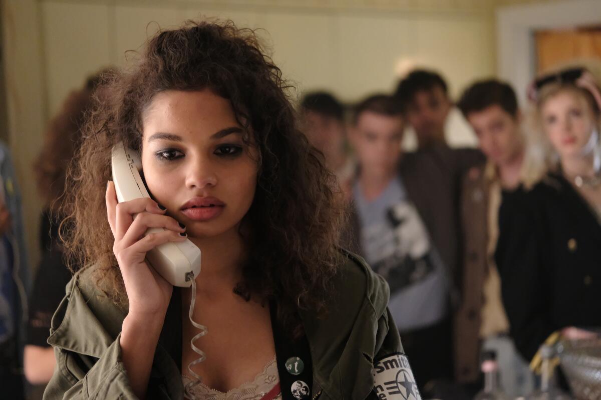 Helena Howard holds a phone to her ear with a crowd behind her