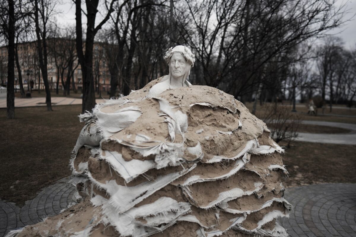 A statue is covered with sand bags to protect it from the Russian shelling in Kyiv, Ukraine, Thursday, March 9, 2023. There are sandbags around the statues and anti-tank obstacles by the side of the streets, trenches in the nearby forests and land mine warnings in the woods. Signs painted onto walls point to the nearest shelter, while air raid sirens occasionally wail across the city, which still sometimes comes under missile attack. (AP Photo/Thibault Camus)