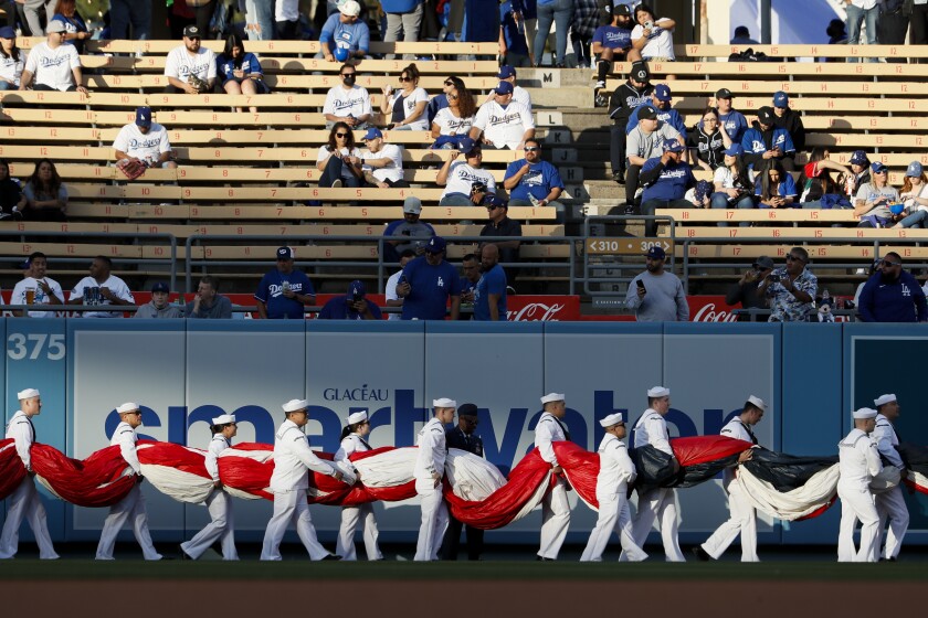 Servicemen carry a large American flag onto the field before the game against the Cincinnati Reds at Dodger Stadium