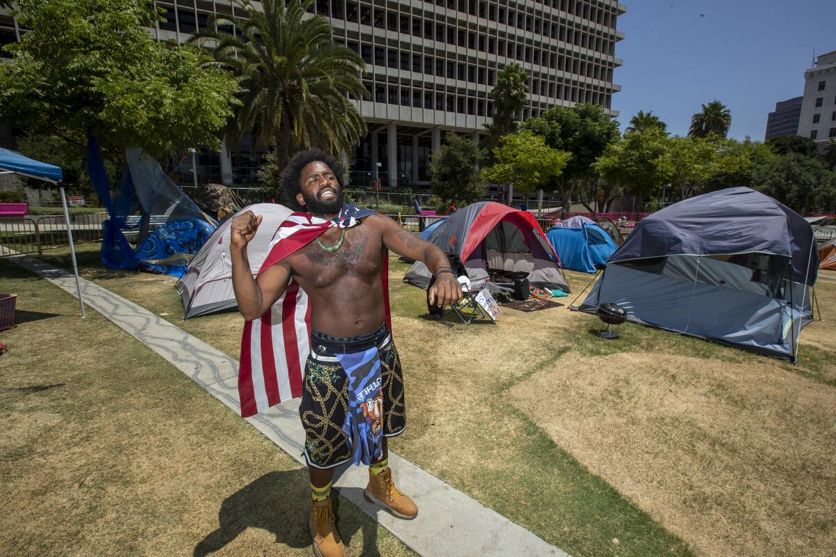 Jason Morales, 34, of Pacoima stands amid the Grand Park camp whose theme is Black unity.