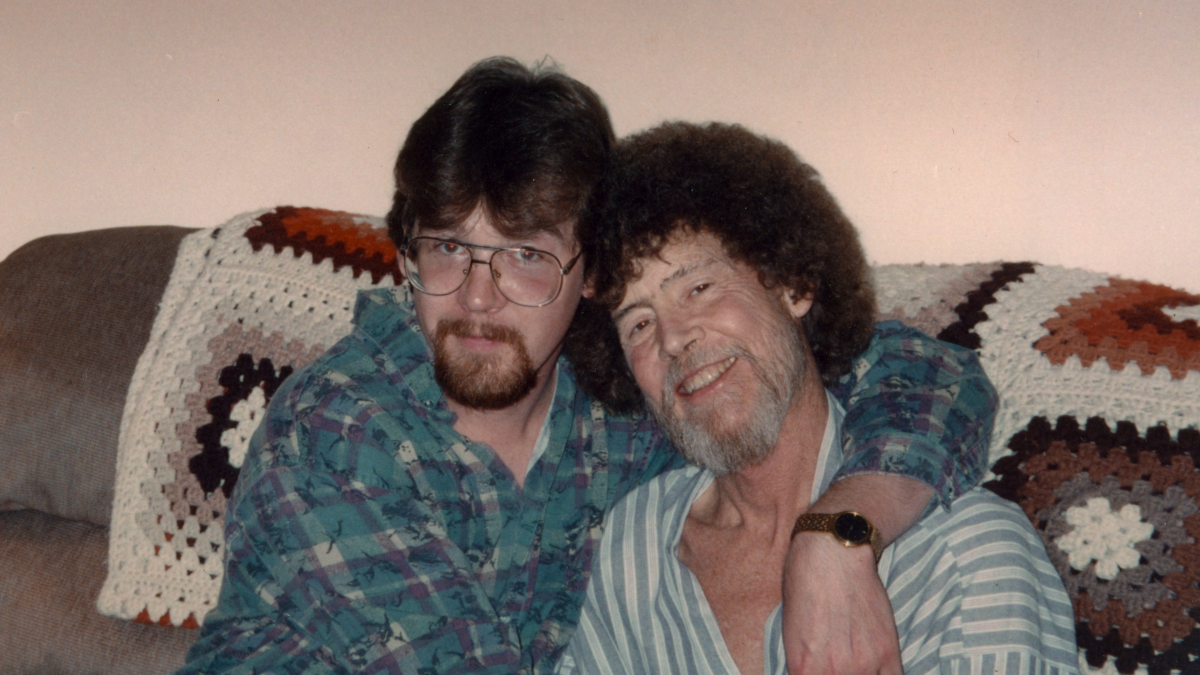 An adult son with his arm around his father in the documentary "Bob Ross: Happy Accidents, Betrayal & Greed."