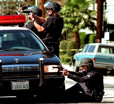 LAPD officers are prepared to fire at the intersection of Vanowen Street and Gentry Avenue in North Hollywood during a standoff with bank robbers who were holding several people hostage. (1997)