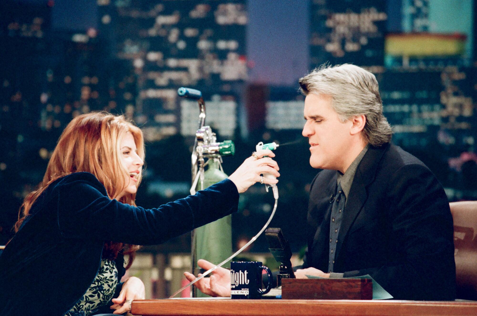  Kirstie Alley playfully sprays Jay Leno with a nozzle.