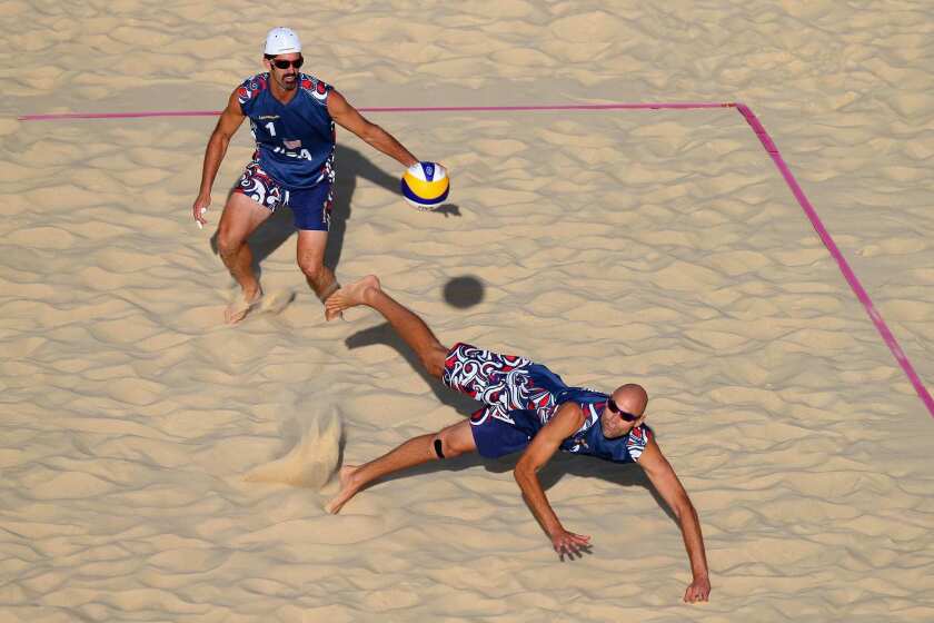 Phil Dalhausser of the United States dives for the ball in front of teammate Todd Rogers. Italy upset the United States to advance in the tournament.