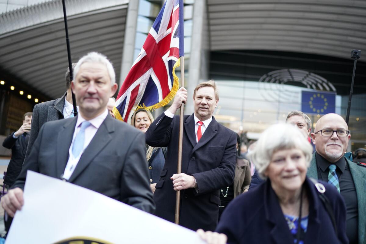 Jonathan Bullock, a British member of the European Parliament, holds the Union Jack flag as he leaves the European Parliament in Brussels