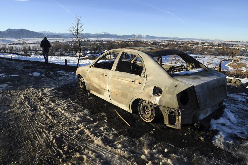 A burned car is abandoned on a hilltop overlooking Superior, Colo., on Sunday, Jan. 2, 2022. (AP Photo/Thomas Peipert)