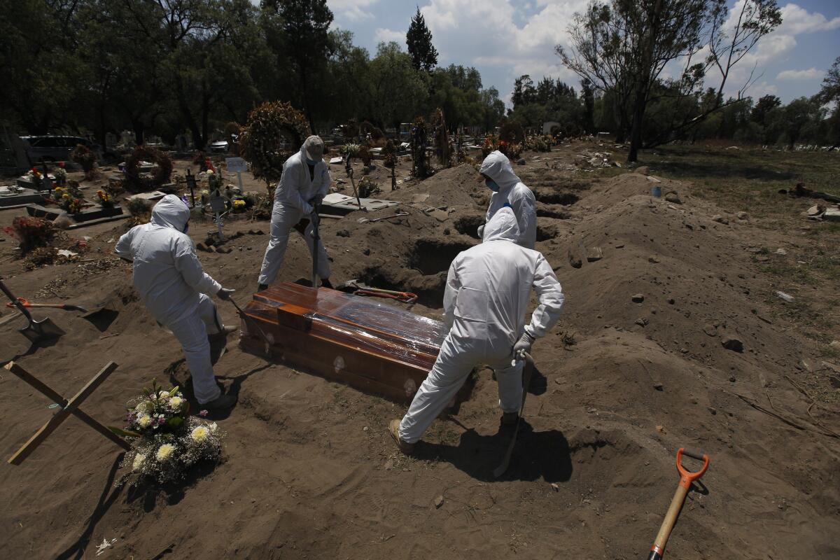 Cemetery workers in protective gear lower a coffin containing a COVID-19 victim in Mexico City.
