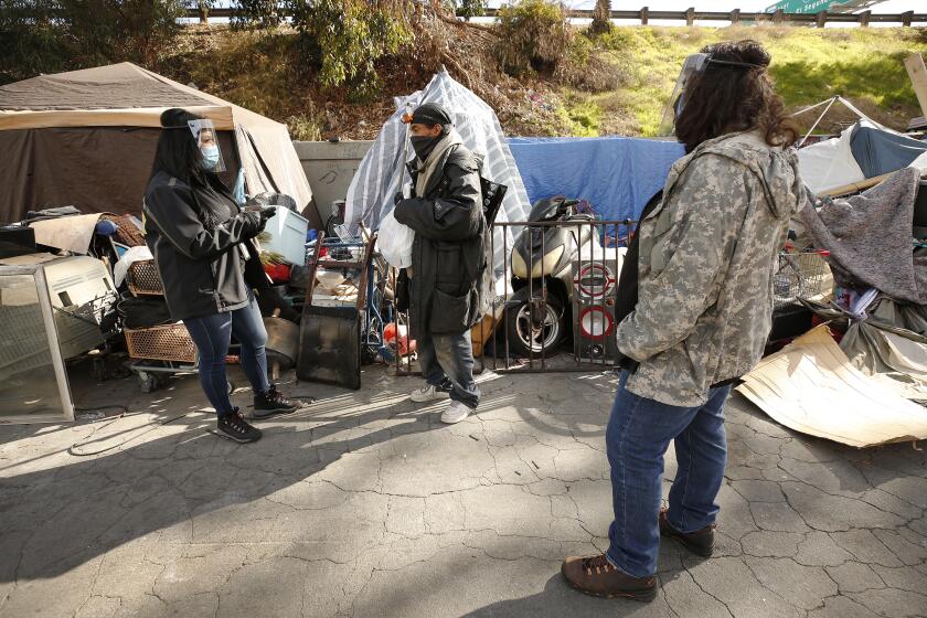 LOS ANGELES, CA - JANUARY 28: Marisol Barroso, left, and Jaime Montoya, right, (HET) Homeless Engagement Team Outreach Workers talk to a client named Ace, middle, and input his information as they join outreach workers from various agencies working with the homeless population as they use a smartphone app called Hot Spots that distributes information about the people they meet. The outreach teams canvas an area on Irwin Ave at West 101st Street in Lennox near LAX. With the Point in Time count canceled this year because of the pandemic, some are suggesting it's time to move on from the massive volunteer to a more data-savvy method using information gathered by outreach workers. Lennox on Thursday, Jan. 28, 2021 in Los Angeles, CA. (Al Seib / Los Angeles Times).