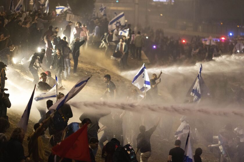 Israeli police use a water cannon to disperse demonstrators blocking a highway during a protest against plans by Prime Minister Benjamin Netanyahu's government to overhaul the judicial system in Tel Aviv, Israel, Monday, March 27, 2023. Tens of thousands of Israelis have poured into the streets across the country in a spontaneous outburst of anger after Prime Minister Benjamin Netanyahu abruptly fired his defense minister for challenging the Israeli leader's judicial overhaul plan. (AP Photo/Oren Ziv)