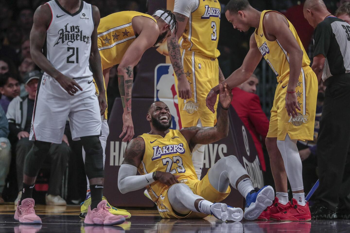 Lakers forward LeBron James is helped up by teammates after falling to the court.