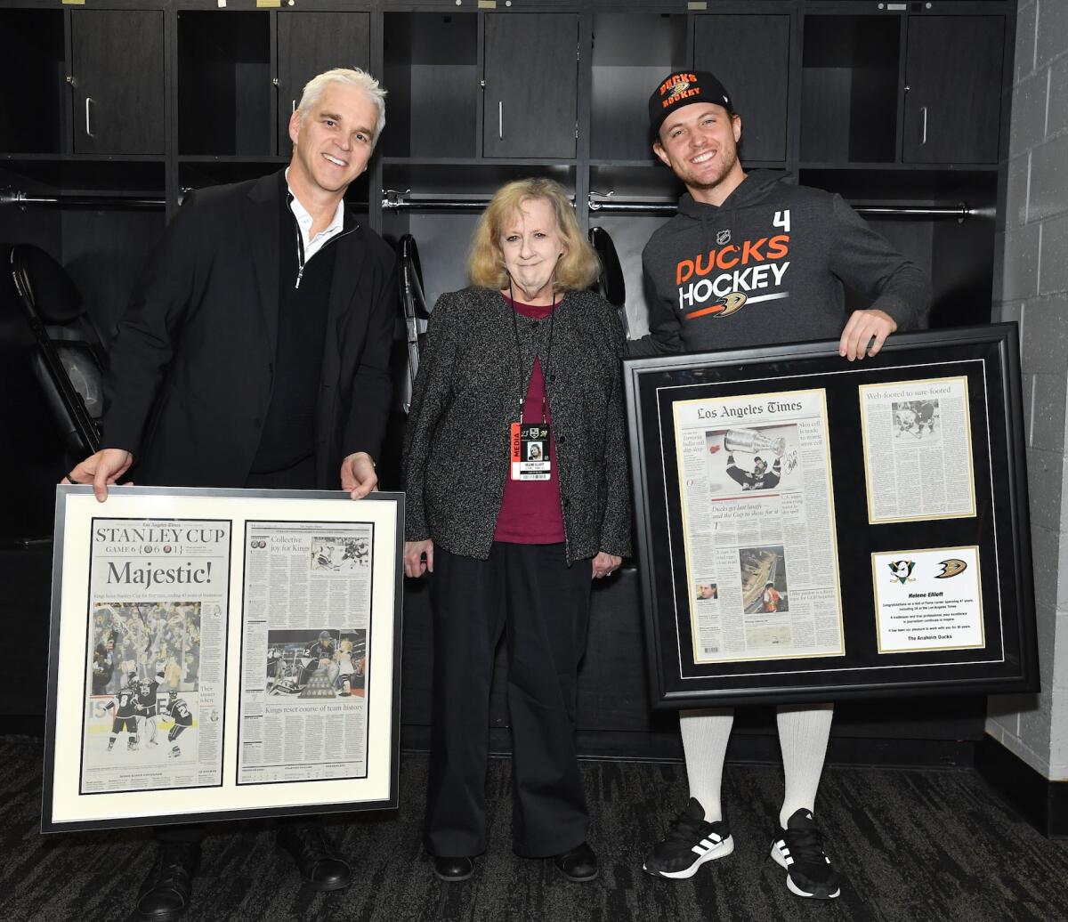The Kings' Luc Robitaille and Ducks' Cam Fowler present Times columnist Helene Elliott with frames copies of her work