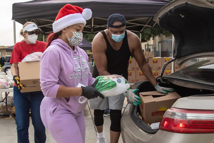 SAN DIEGO, CA - DECEMBER 23: Lane Hollerbach, Lorraine Ward, and Claude Edwards load food into cars during a drive-thru distribution event on Wednesday, Dec. 23, 2020 at Bayview Church in San Diego, CA. (Jarrod Valliere / The San Diego Union-Tribune)
