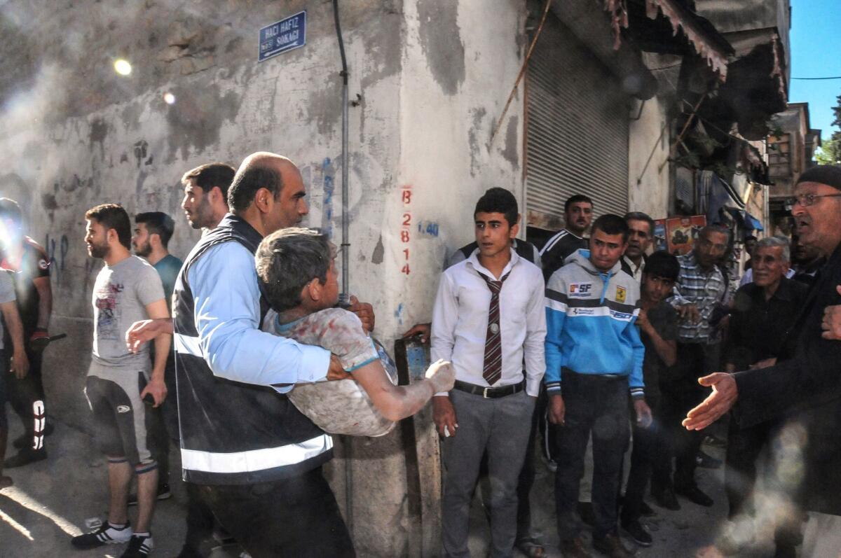 A man carries an injured child after four rockets fired from Syria slammed into Kilis on April 18.