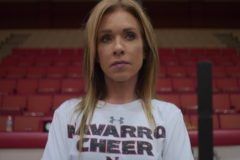 A woman in a Navarro College t-shirt stands with auditorium seats in the background