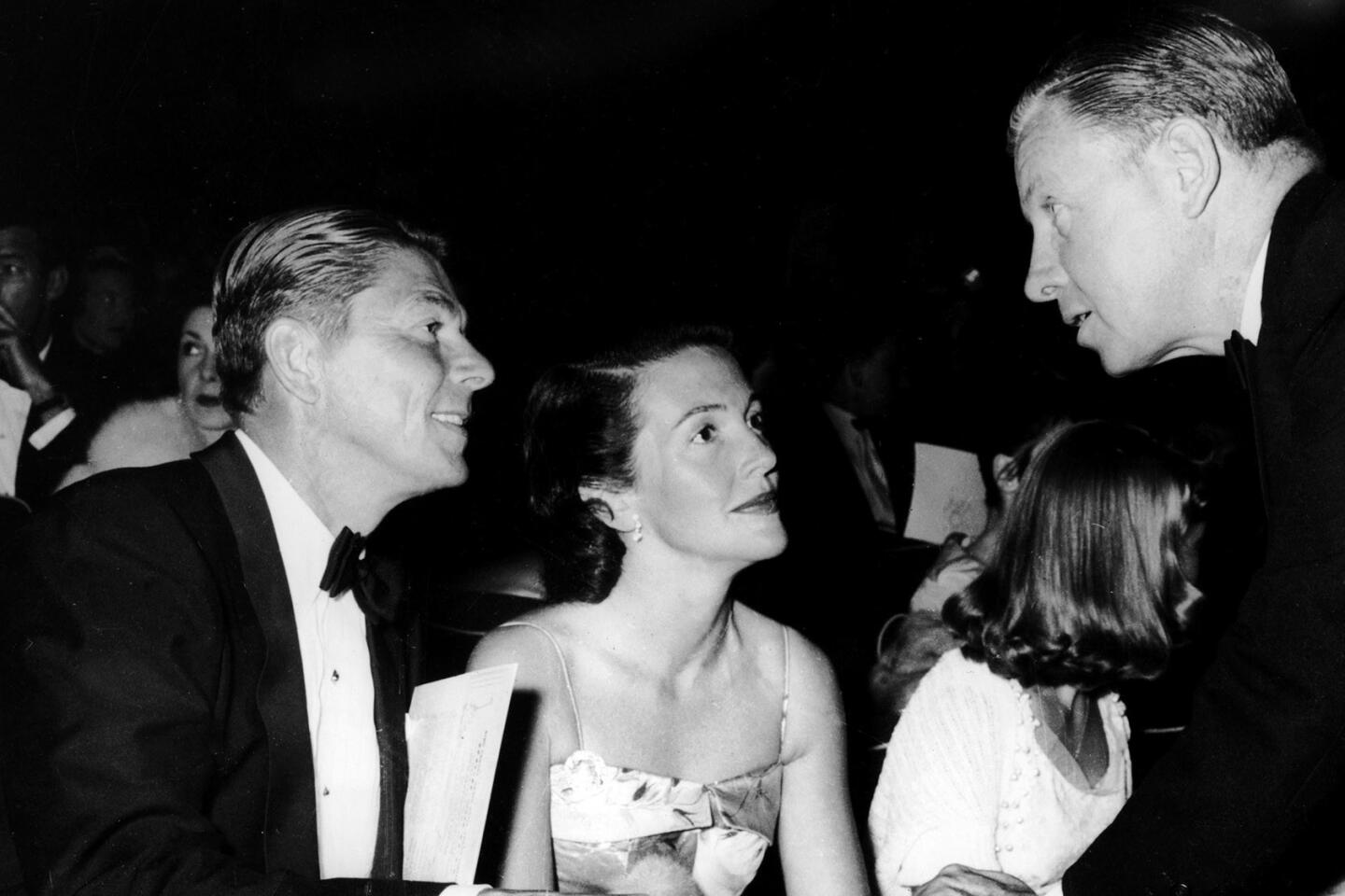 American actor and future president Ronald Reagan (1911 - 2004) sits with his wife, actress Nancy Reagan, as the par talk with fellow actor and future US Senator George Murphy (1902 - 1992) at the premiere of 'High Society,' July 1956. (Photo by Pictorial Parade/Getty Images)