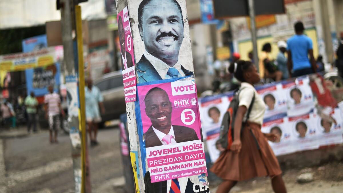 Electoral posters of Haitian presidential candidates Jude Celestin, top, and Jovenel Moise are seen on a street in Port-au-Prince. Moise has won the election, according to preliminary results.