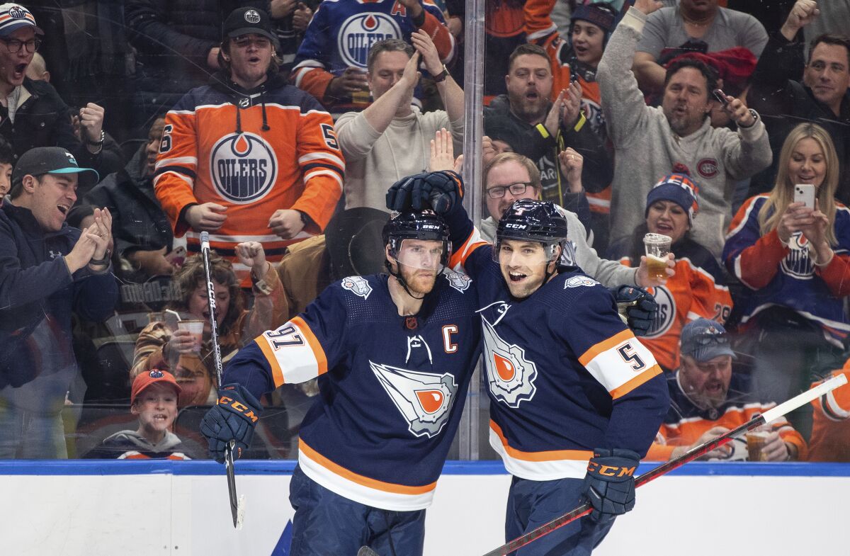 Edmonton Oilers' Connor McDavid (97) and Cody Ceci (5) celebrate a goal against the Chicago Blackhawks during the second period of an NHL hockey game Saturday, Jan. 28, 2023, in Edmonton, Alberta. (Jason Franson/The Canadian Press via AP)