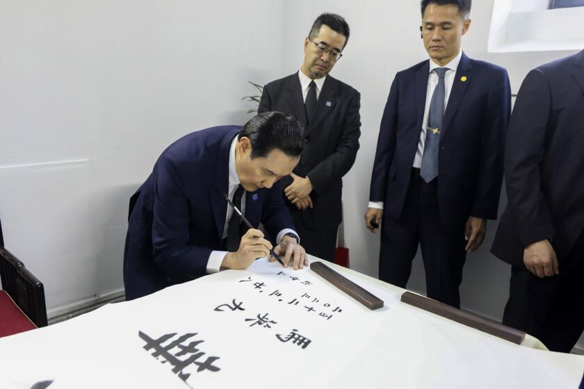 In this photo released by the Ma Ying-jeou Office, Former Taiwan President Ma Ying-jeou, center, writes calligraphy at the Mausoleum of Sun Yat-sen in Nanjing in eastern China's Jiangsu Province, Tuesday, March 28, 2023. Ma departed for a tour of China on Monday, in what he called an attempt to reduce tensions a day after Taiwan lost one of its few remaining diplomatic partners to China. (Ma Ying-jeou Office via AP)