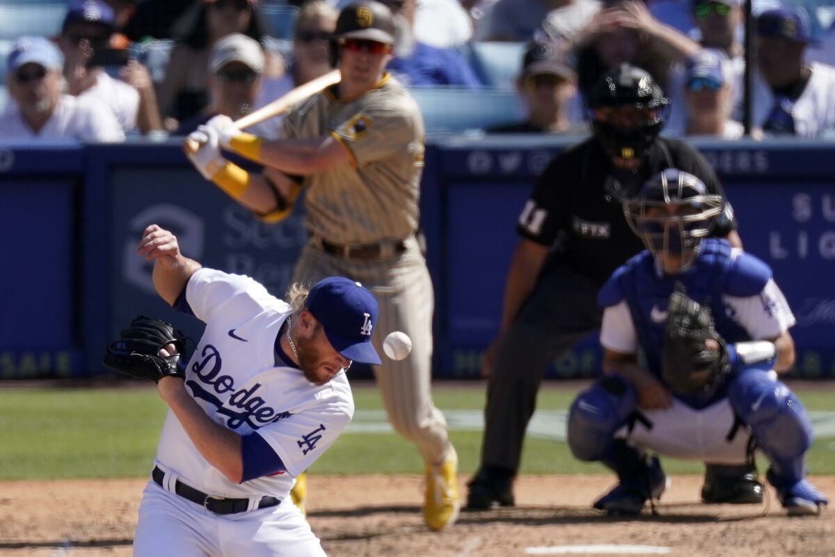 Los Angeles Dodgers relief pitcher Craig Kimbrel, left, is hit by the ball as San Diego Padres' Jake Cronenworth, left, hits a single as catcher Austin Barnes, right, and home plate umpire home plate umpire Charlie Ramos watch during the ninth inning of a baseball game Sunday, July 3, 2022, in Los Angeles. (AP Photo/Mark J. Terrill)