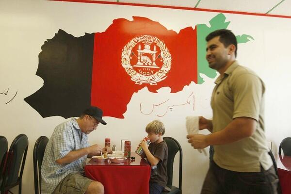 Mike Prado and his son Samuel have lunch at Afghan Express as co-owner Najeeb Shinwari walks by.
