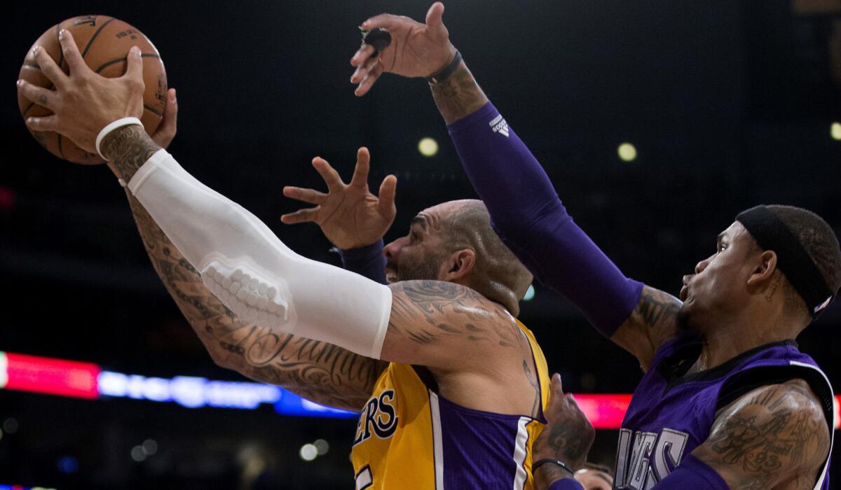 Lakers forward Carlos Boozer drives to the basket against Kings guard Ben McLemore, right, and forward Derrick Williams, rear, in the first half Wednesday night at Staples Center.