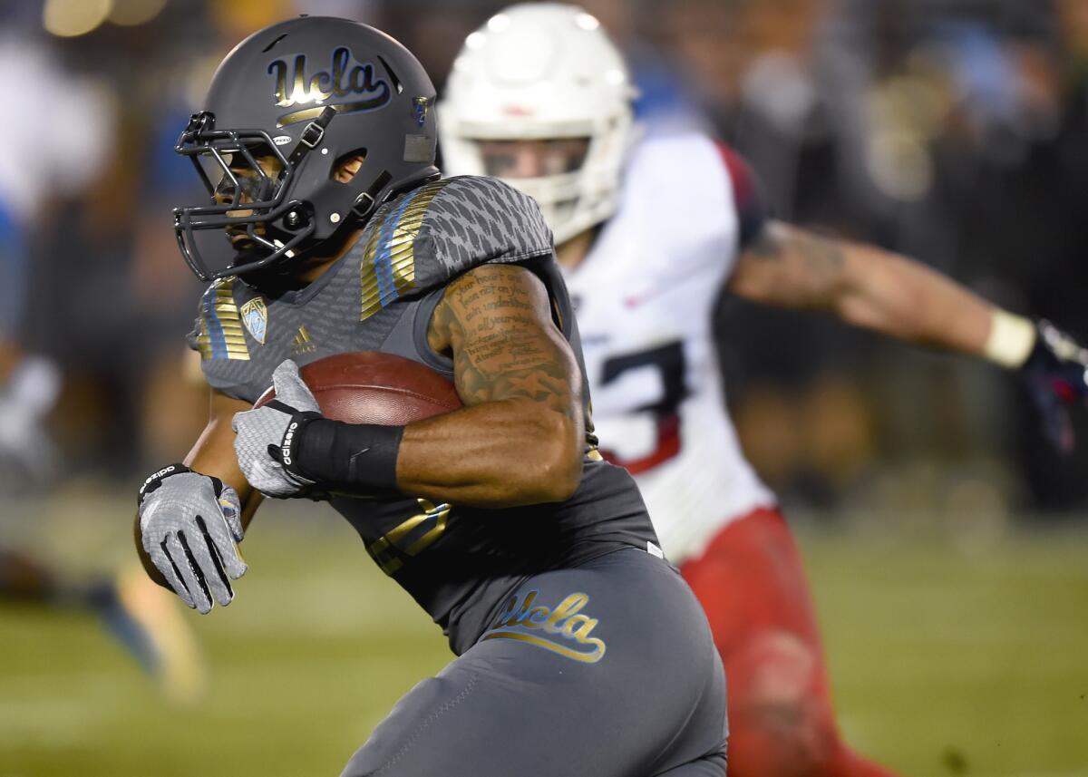 UCLA running back Nate Starks gets past Arizona linebacker Scooby Wright III on a carry in the first half of the Bruins' 17-7 win over the Wildcats on Nov. 1.