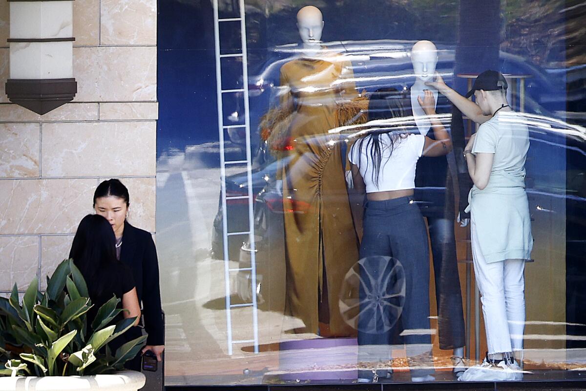Workers dress mannequins in a Nordstrom window