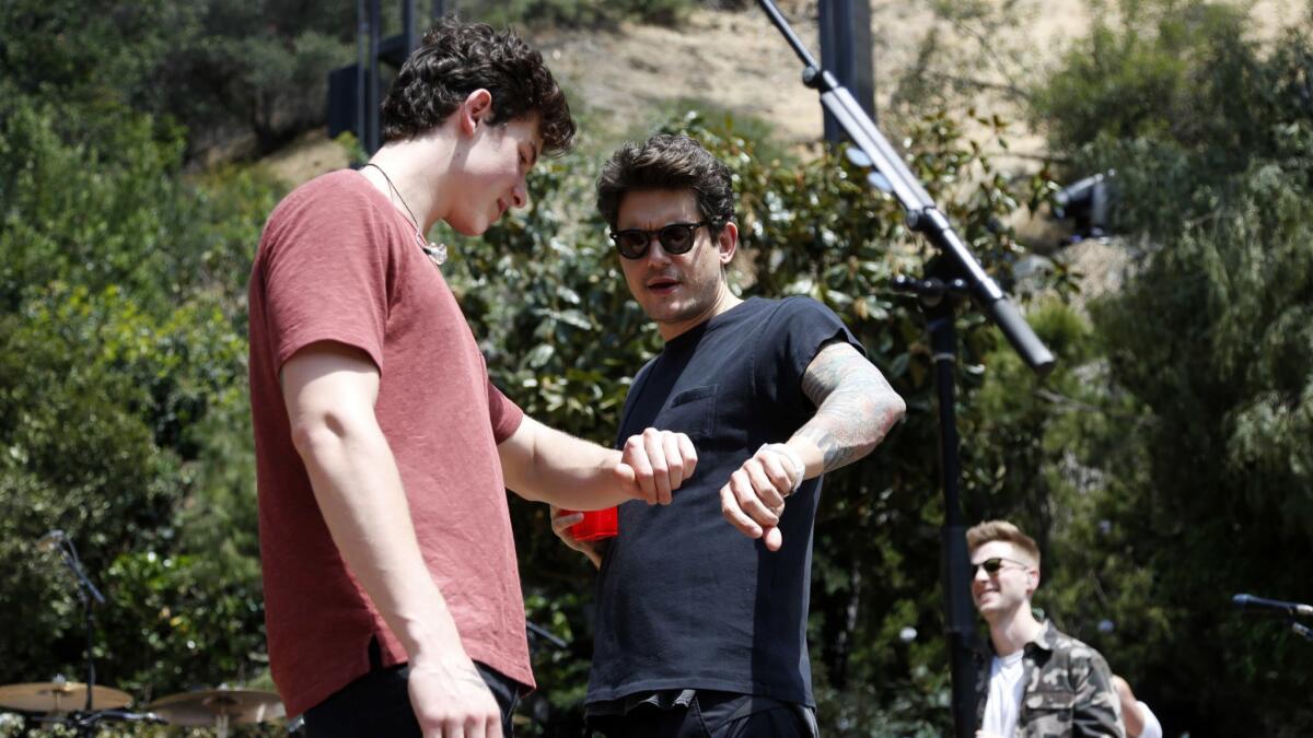 Shawn Mendes and John Mayer comparing wristwatches.