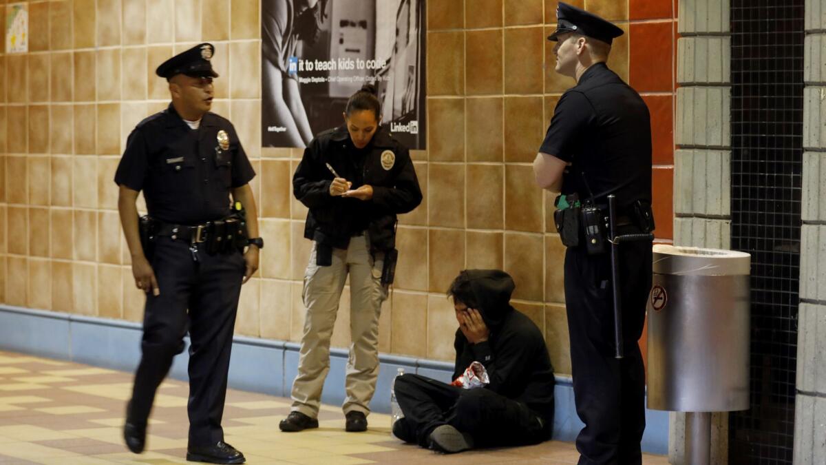 LAPD officer Ian Cochran talks with Joshua Gonzalez sitting on the floor in the subway in Los Angeles. (Francine Orr / Los Angeles Times)