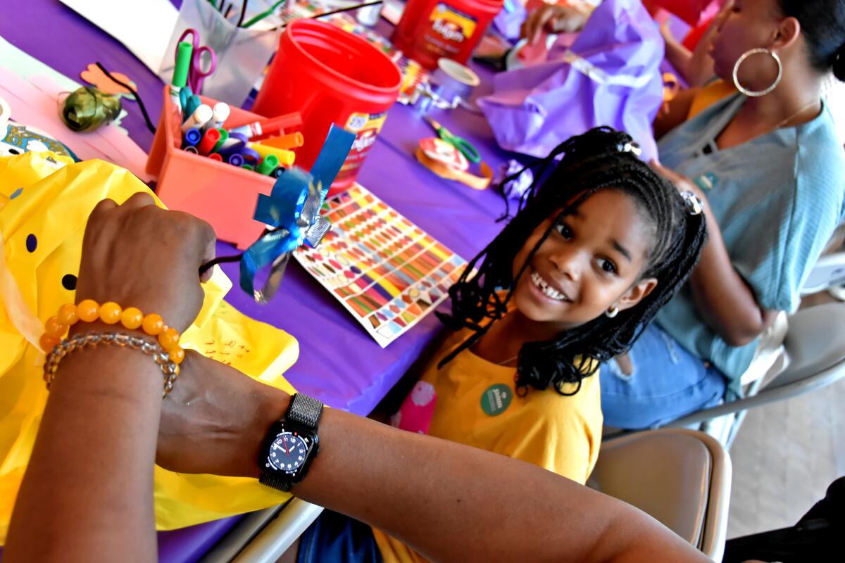 A girl making crafts at a table covered in paper and markers.