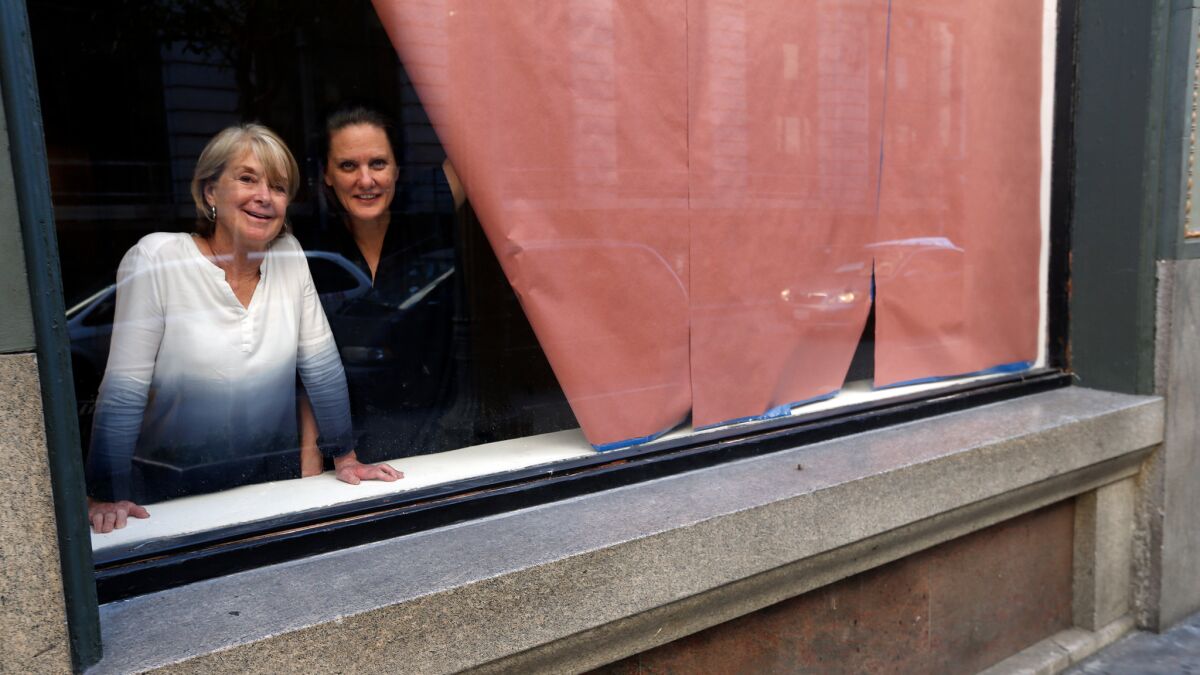 Artists Suzanne Lacy, left, and Andrea Bowers in the windows of the Main Museum in downtown L.A. in October.