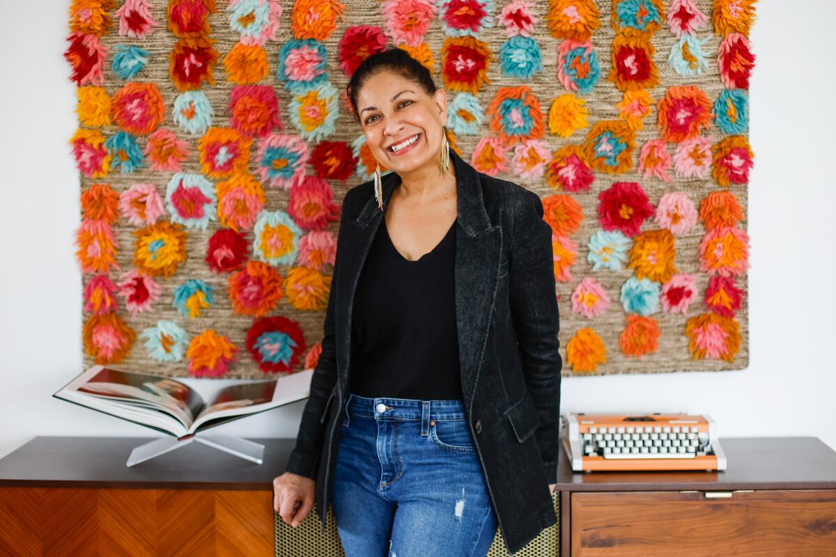 Documentary filmmaker Nisha Pahuja poses for a portrait before a colorful wall hanging.