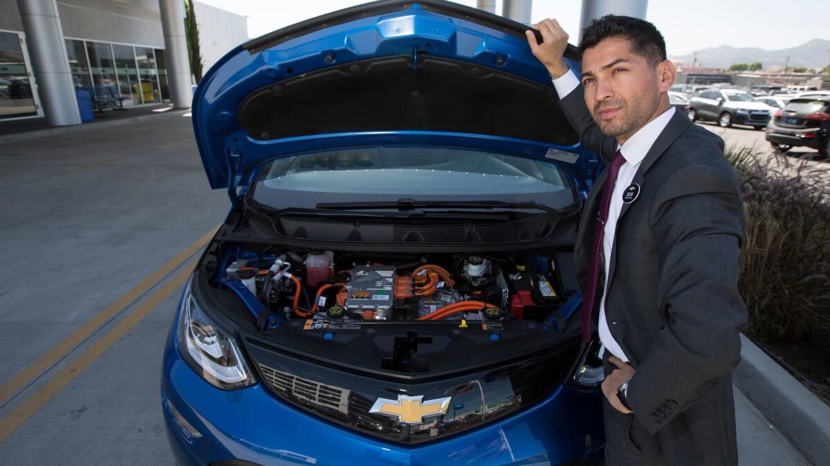 Oscar Gutierrez of Community Chevrolet in Burbank under the hood of a Bolt electric car. (Brian van der Brug / Los Angeles Times)