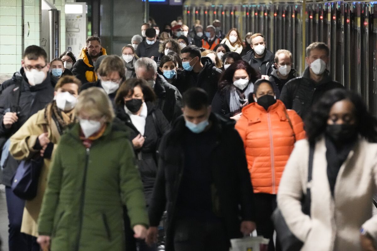 Commuters wearing masks as a COVID-19 precaution arrive at a Berlin transport station.