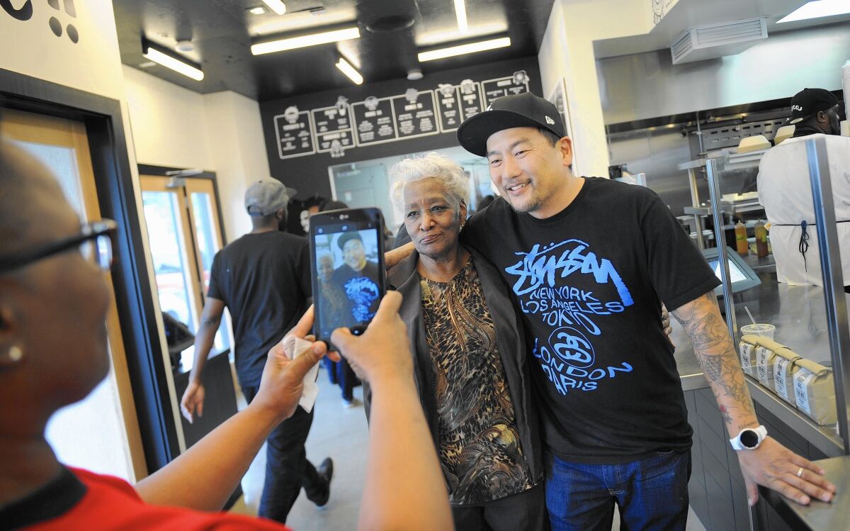 Tabitha O'Neal, left, takes a photo of her mother, Delores, with chef and Locol co-founder Roy Choi at the planned chain's first location in Watts.