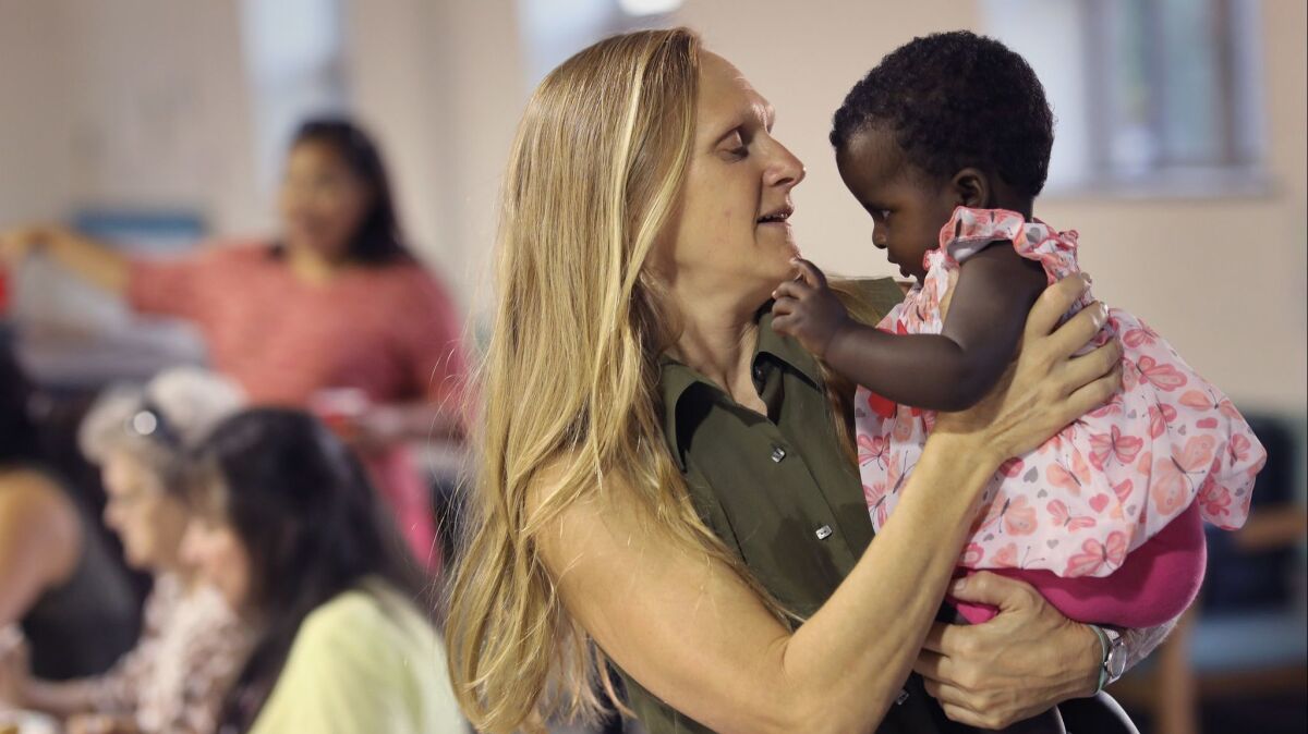 Portland Adult Education instructor Catherine Murray holds Ana, 4 months, the daughter of a Congolese refugee, on Aug. 27 in Sipayik, Maine.