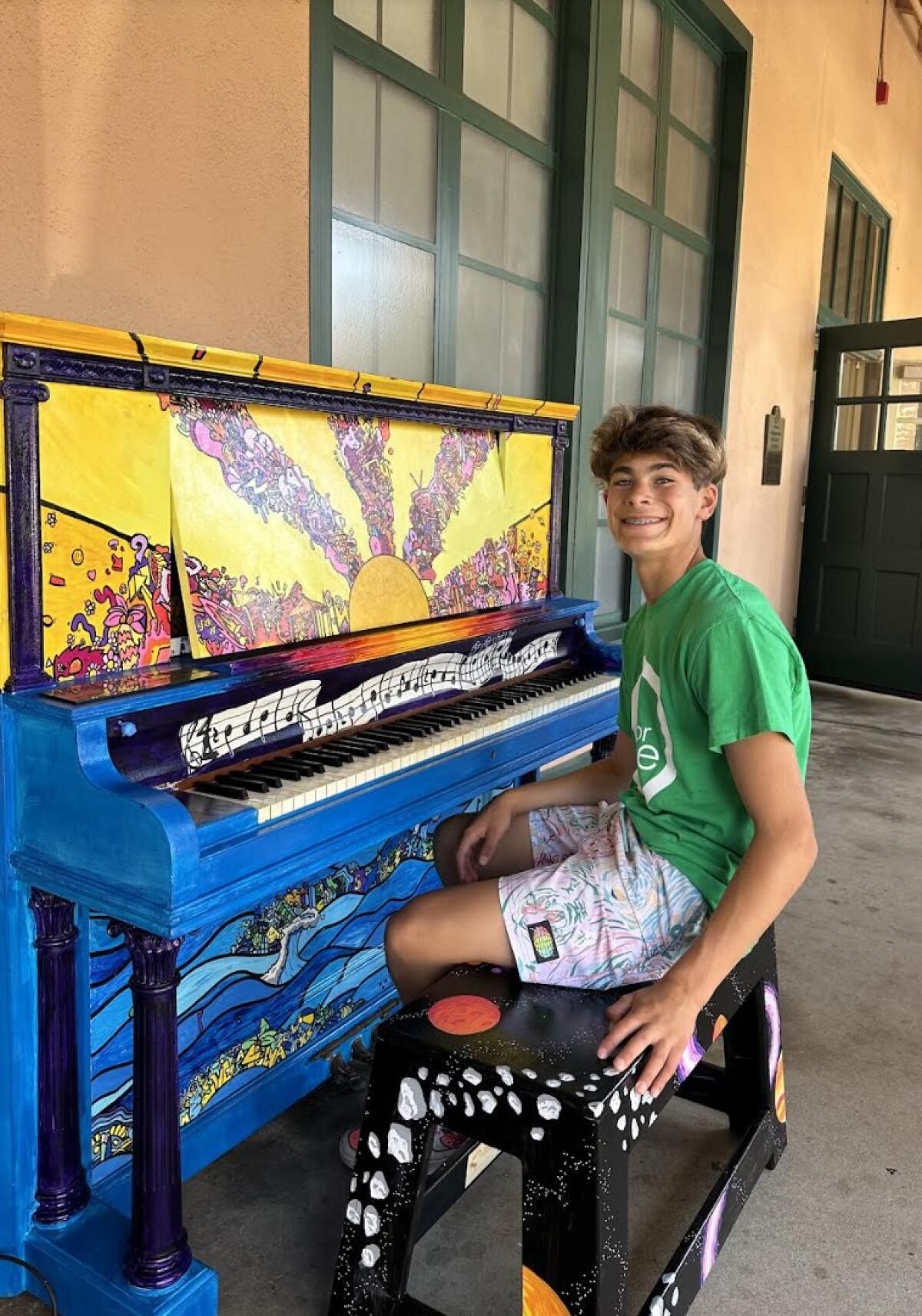 Liam Koett sits at Liberty Station in Point Loma with the piano he hand-painted as a project with friend Makena Stumpo.