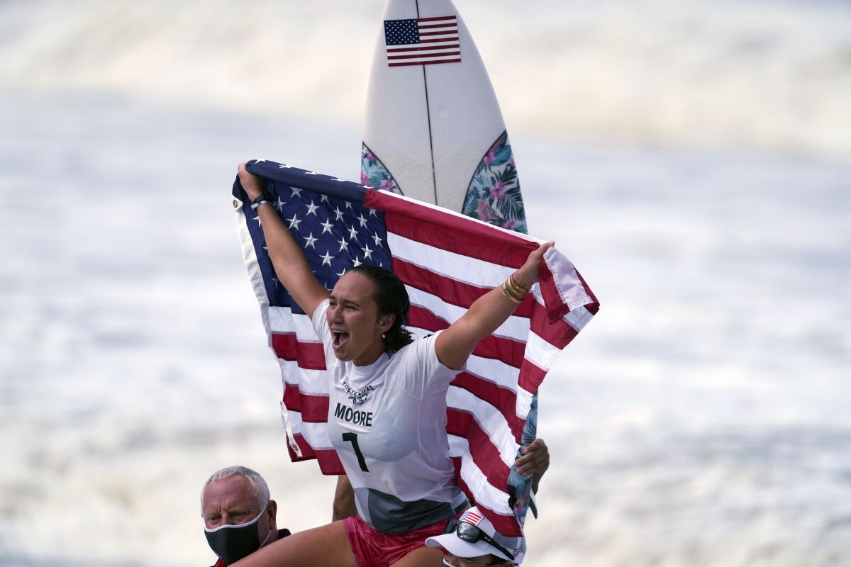 FILE - Carissa Moore, of the United States, celebrates winning the gold medal of the women's surfing competition at the 2020 Summer Olympics, July 27, 2021, at Tsurigasaki beach in Ichinomiya, Japan. Moore won the AAU James E. Sullivan Award as the nation’s most outstanding college or Olympic athlete. Moore is the first surfer and first native Hawaiian to win the 92nd annual award. She was presented the trophy on Thursday in Honolulu. (AP Photo/Francisco Seco, File)