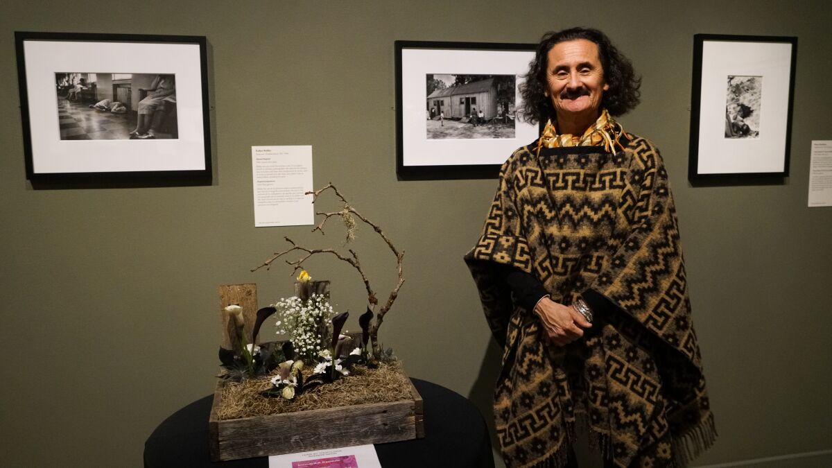 Armando Argandona posa junto a su diseño floral para Art Alive inspirado en la fotografía de atrás.