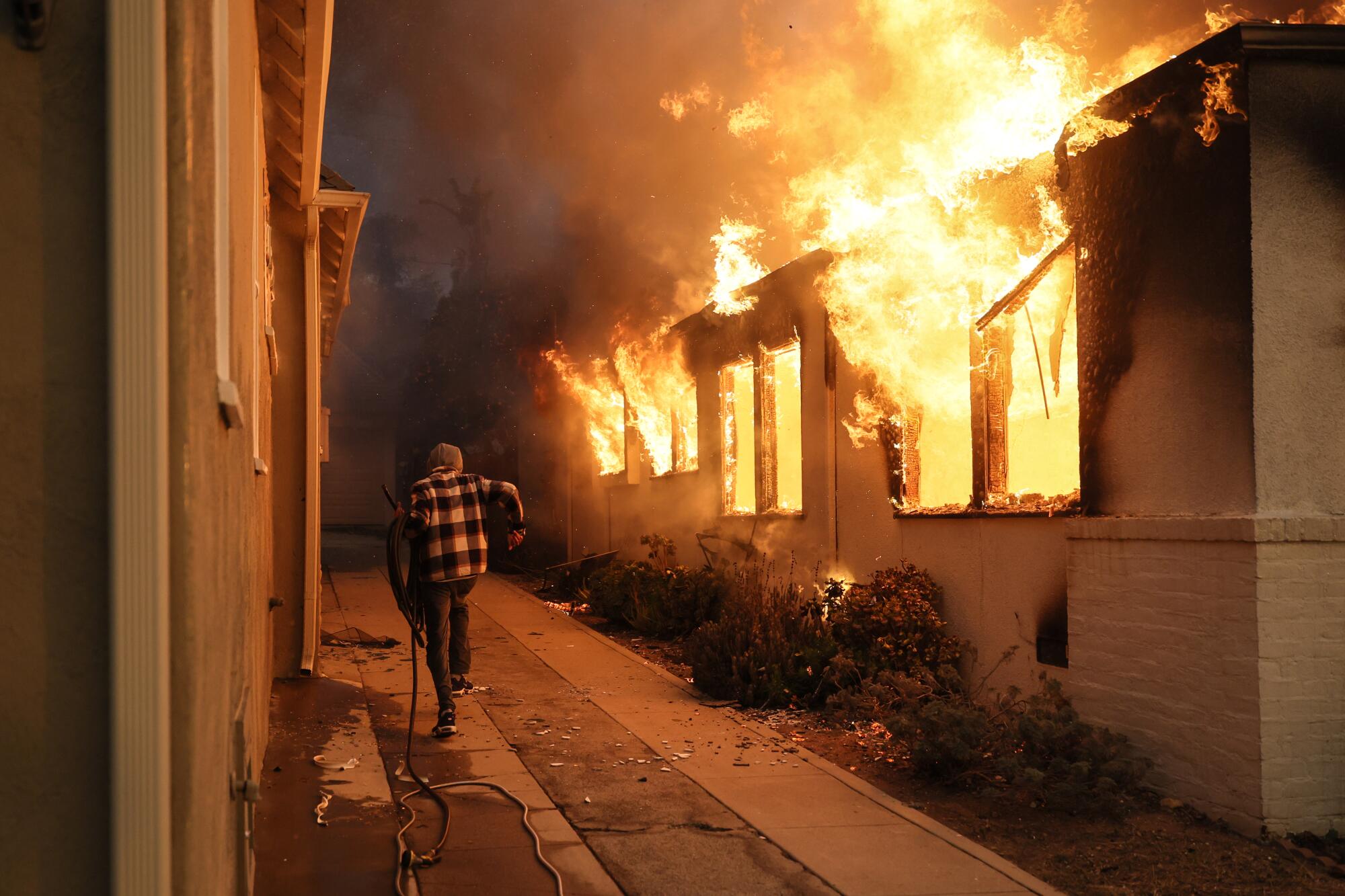 A man next to a house on fire