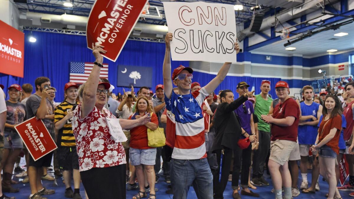 People hold signs while waiting for President Trump to speak at a campaign rally for South Carolina Gov. Henry McMaster in West Columbia, S.C., on Monday.