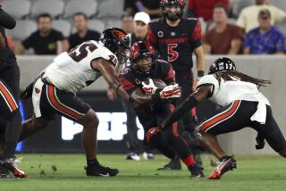 San Diego State running back Marquez Cooper carries the ball and is tackled by two Oregon State players