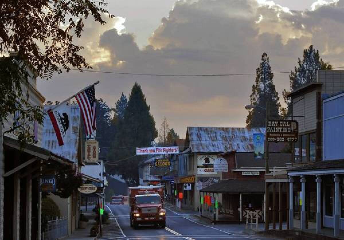 California Department of Forestry crew trucks move through Groveland last week at dawn under a banner that reads "Thank you Fire Fighters" on California 120.