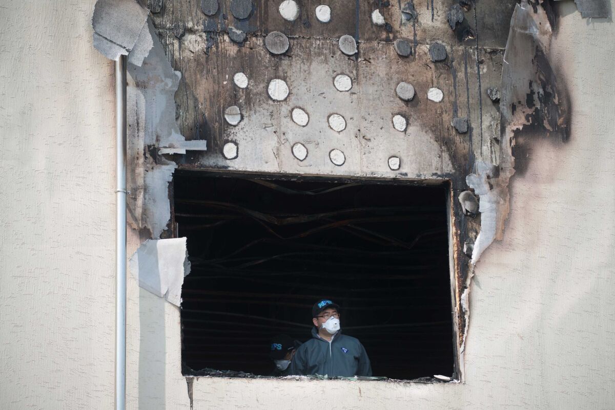 An investigator stands in a window of the fire-damaged Hyosarang nursing home near Janseong.