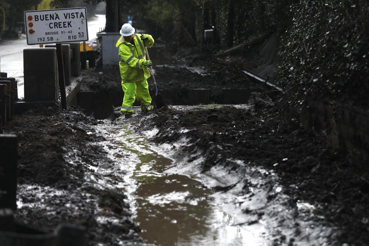 Cal Portland construction worker Tanner Casner clears mud away to let runoff from a recent storm drain into Buena Vista Creek in Montecito.