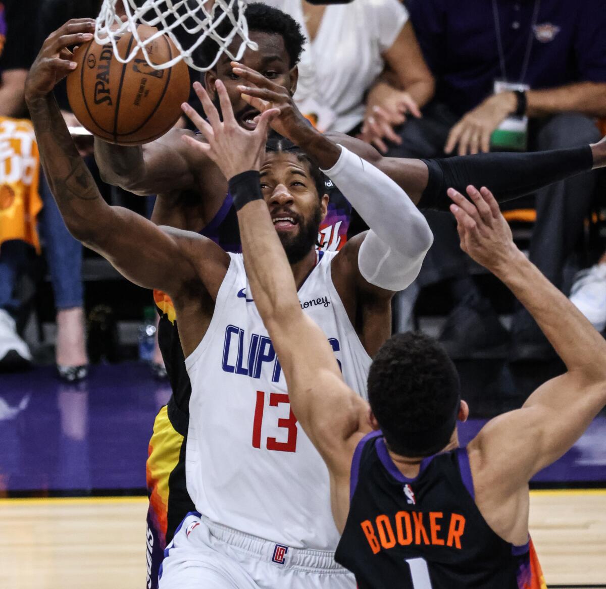 Clippers forward Paul George loses the ball while defended by Suns center Deandre Ayton (22) and guard Devin Booker