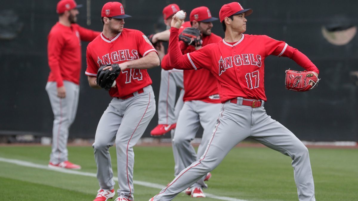 Angels two-way player Shohei Ohtani warms up with other pitchers during his first day of spring training camp at the Tempe Diablo Stadium complex on Wednesday.